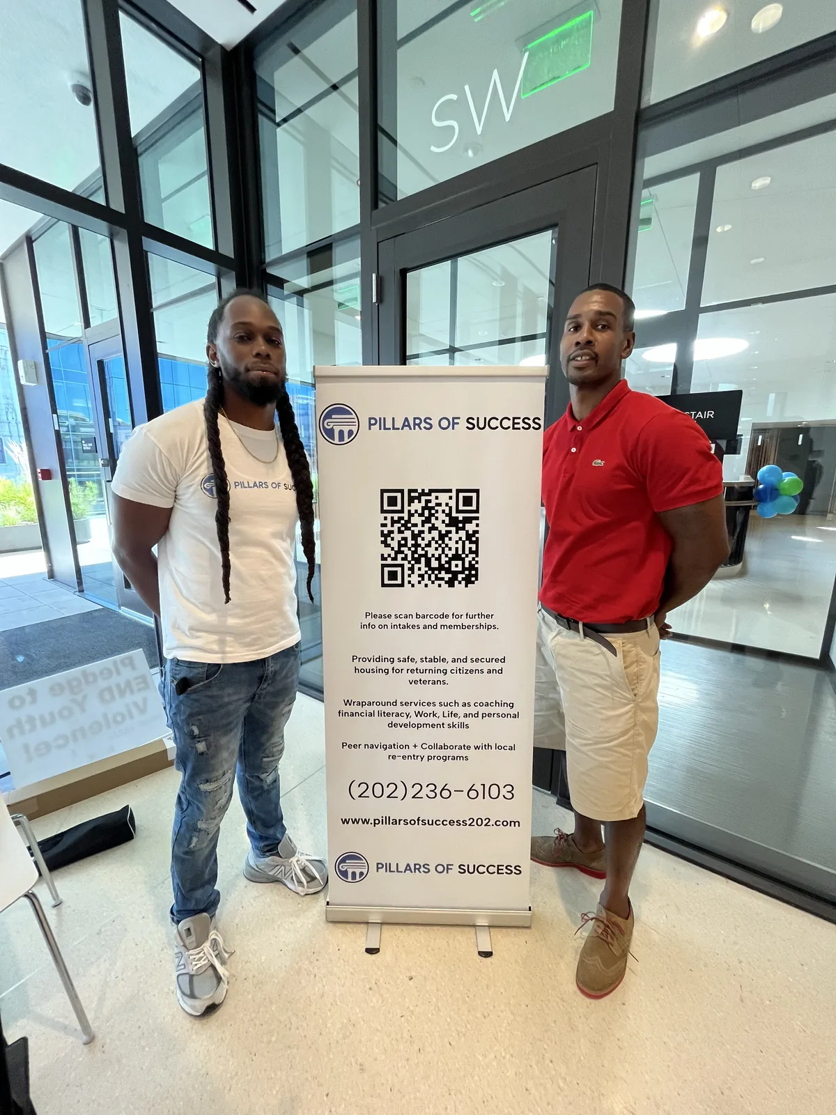 Pillars of Success representatives beside a branded community outreach banner
